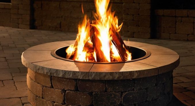 Round stone fire pit with bright flames burning at night