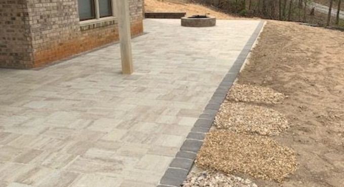Paved walkway beside a brick building, with a narrow border of gray pavers and gravel landscaping.