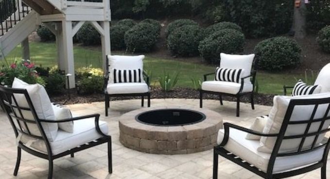 Patio seating around a stone fire pit in a backyard garden