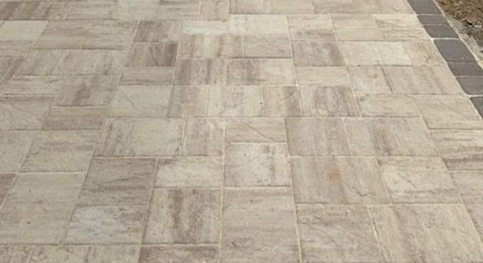 Beige tiled pavement walkway with a stone border on the right