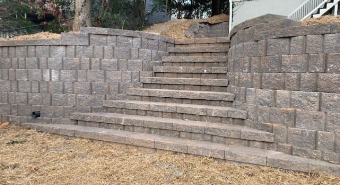 Stone steps between retaining walls leading up a grassy slope outdoors