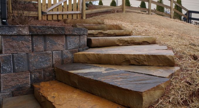 Stone steps built into a landscaped slope beside a retaining wall and gravel path