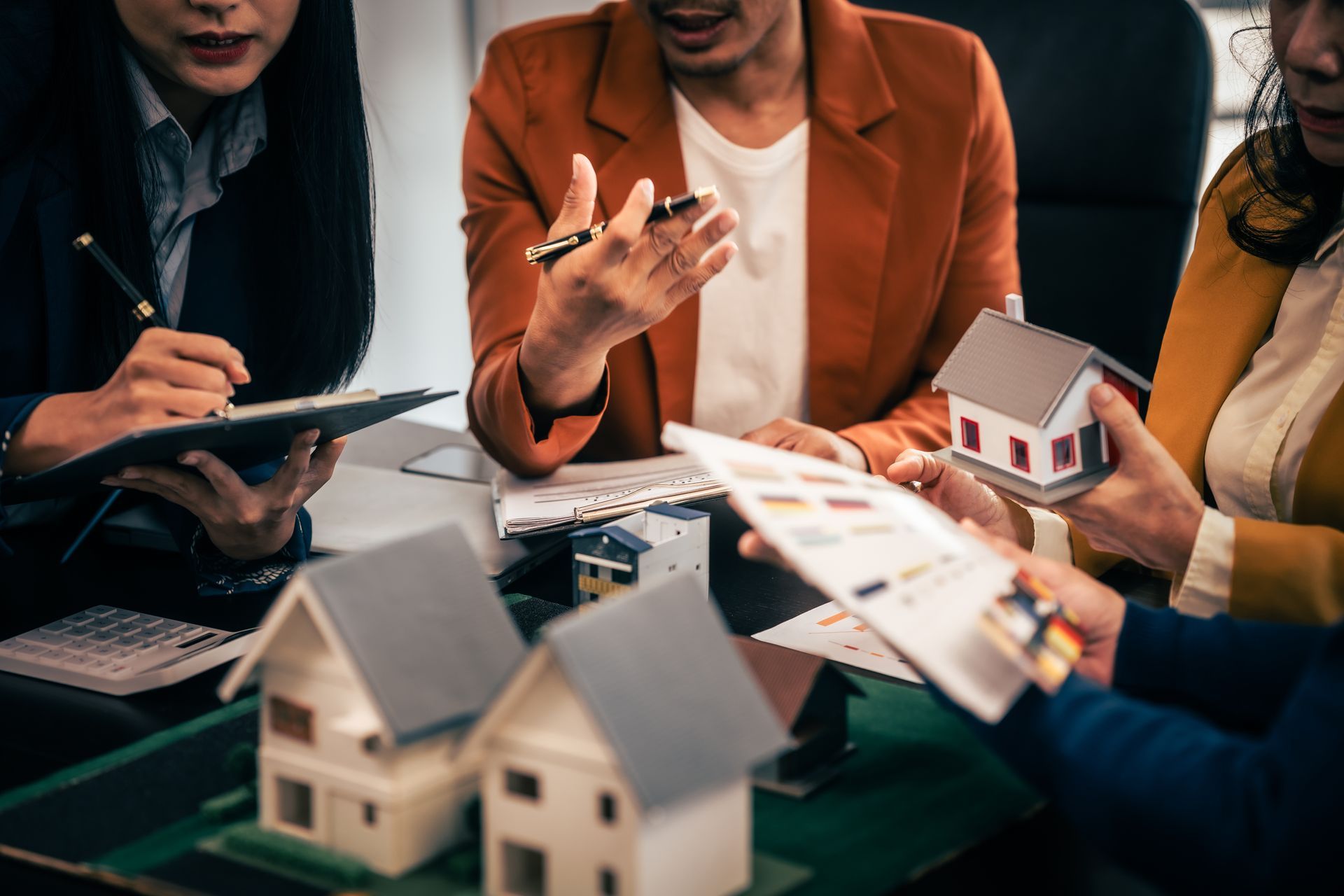 People reviewing house models and property plans at a table