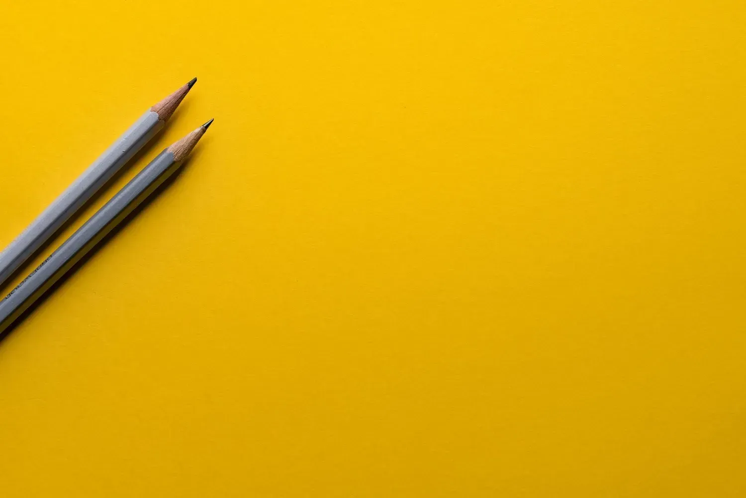 Two pencils on a bright yellow background