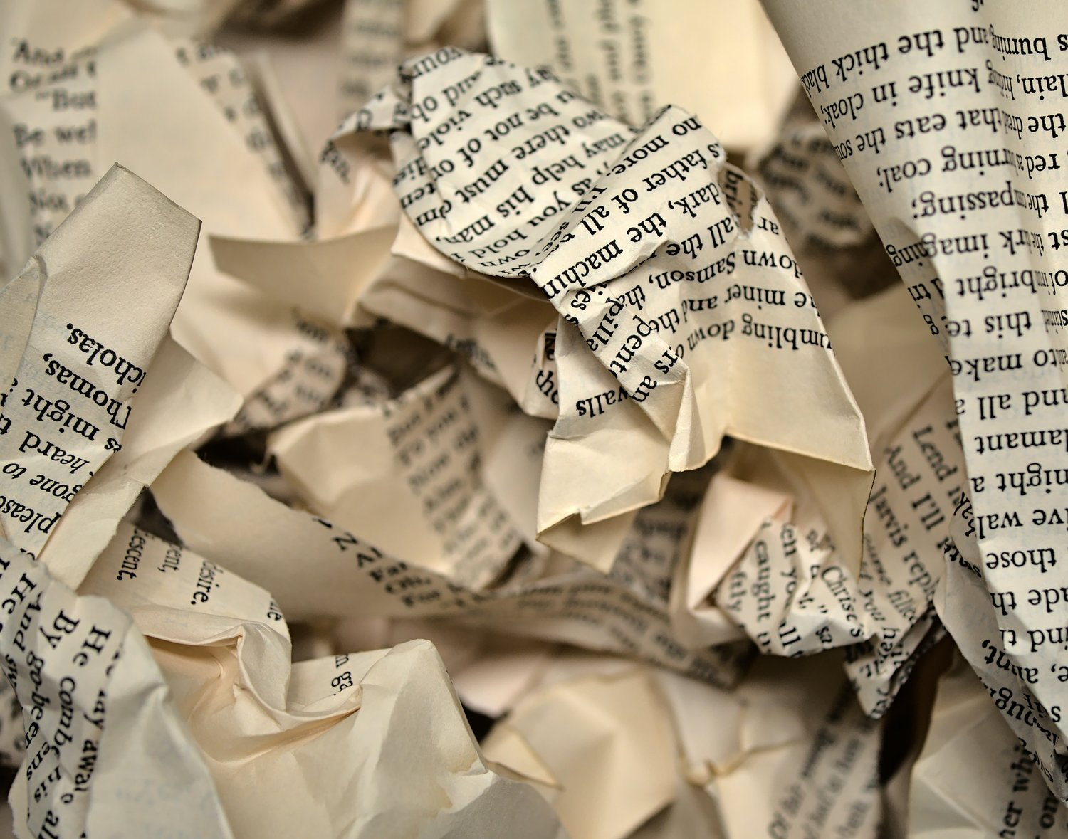 Crumpled newspaper pages in a close-up, beige paper with black printed text.
