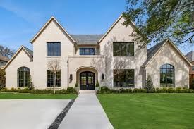 Large white suburban house with gabled roofs, arched windows, and a manicured green lawn