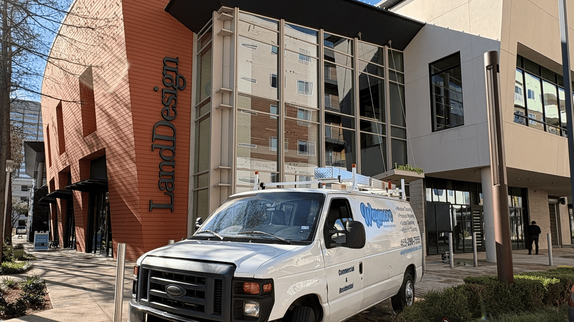 A white service van parked in front of a modern building with a brick facade labeled