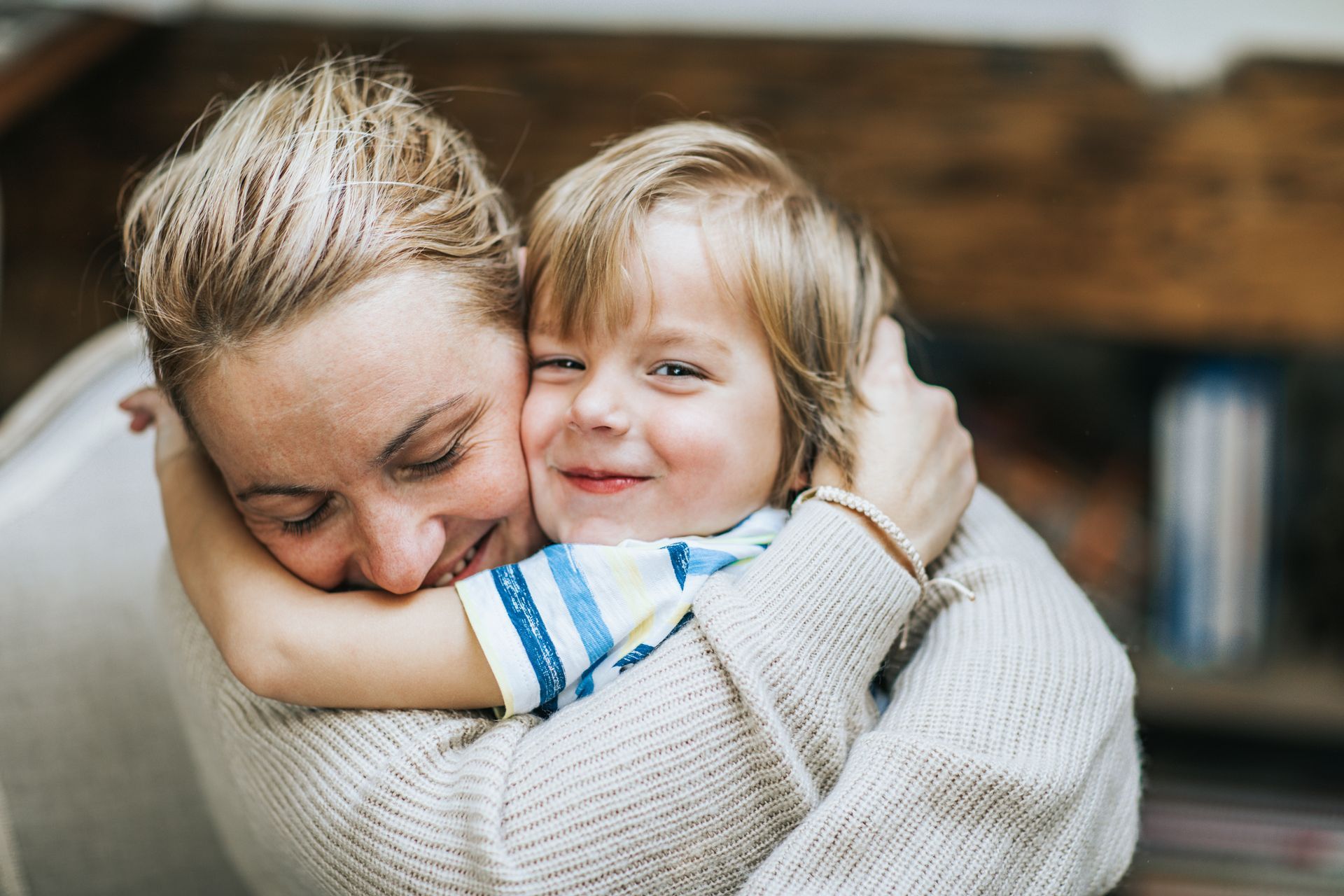 A smiling woman and boy are hugging