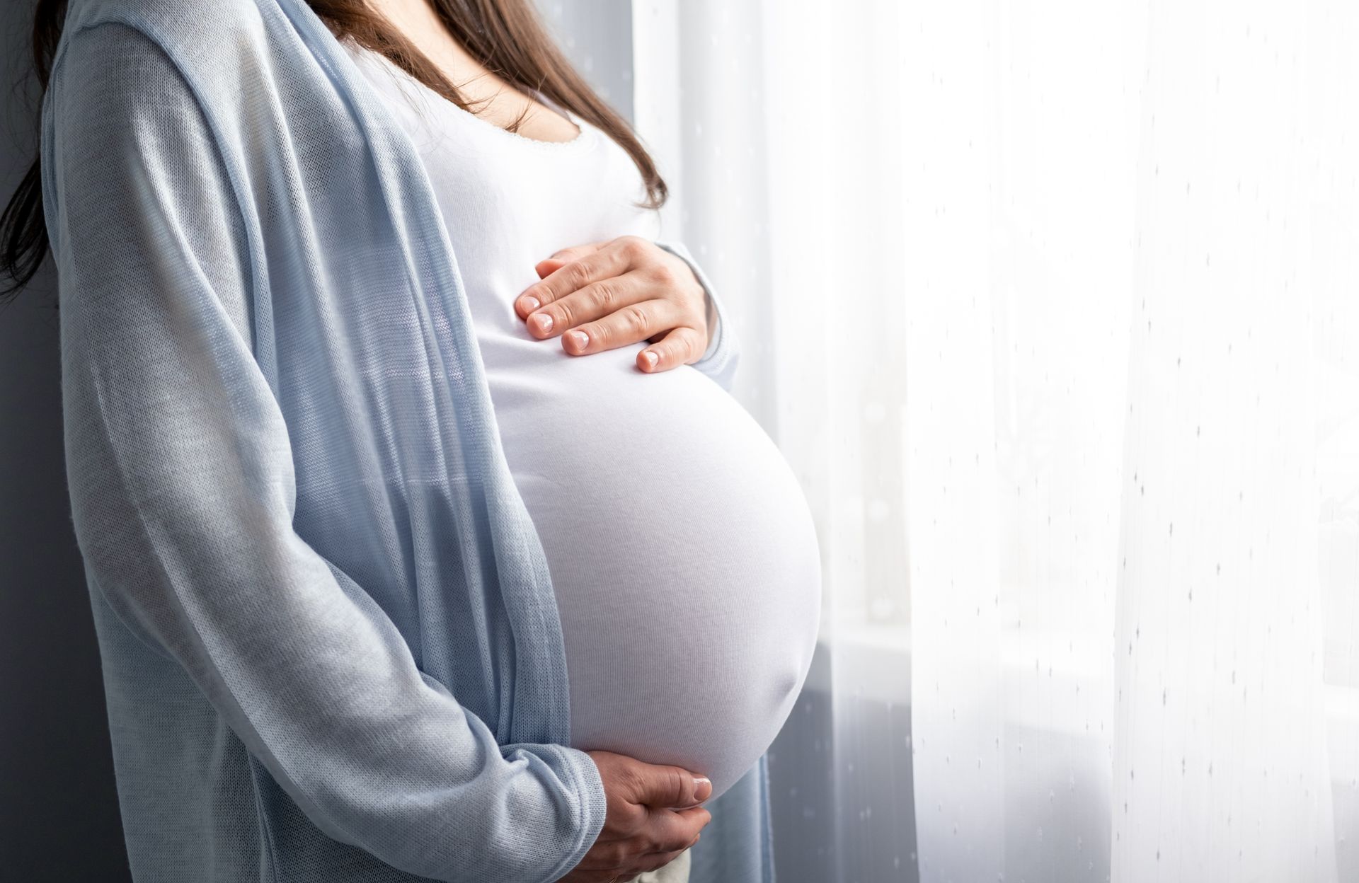 A pregnant woman is cradling her belly