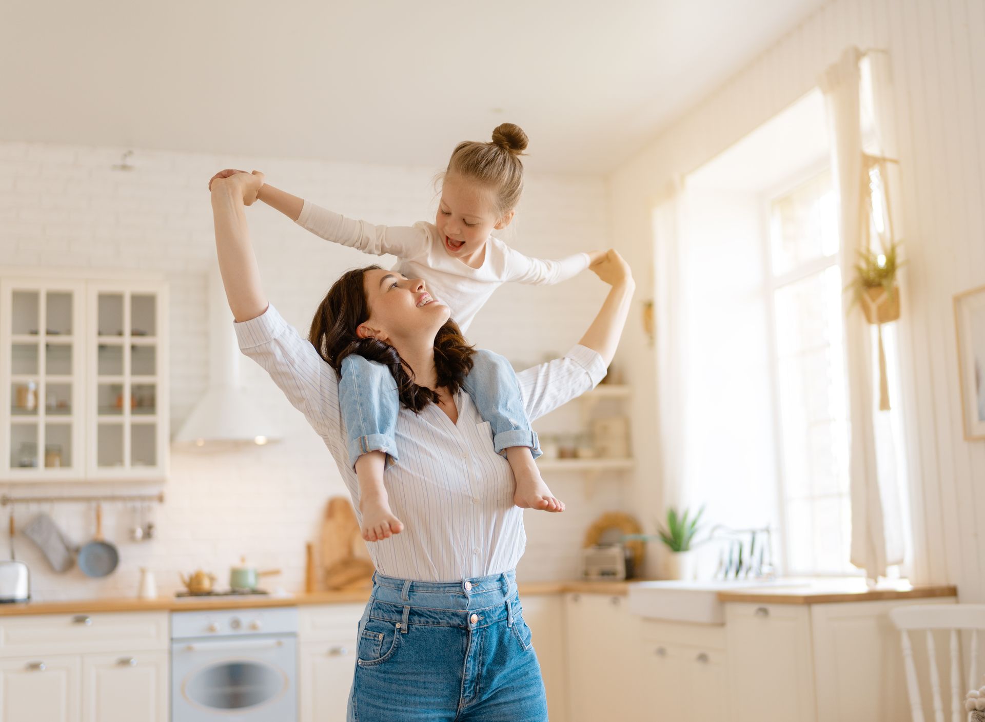 A woman is holding a little girl on her shoulders