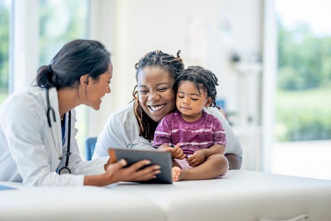 A mother and child are looking at a table with a pediatrician