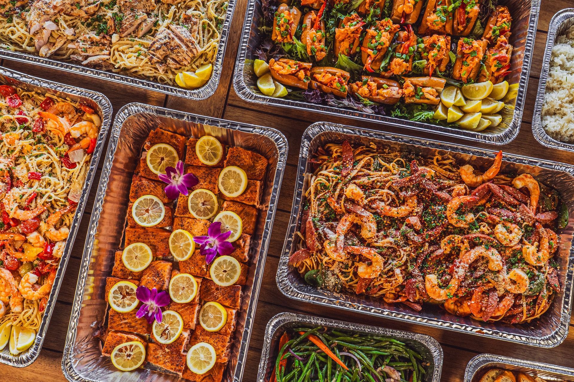Tray of assorted grilled meats and vegetables with colorful garnishes in a buffet spread
