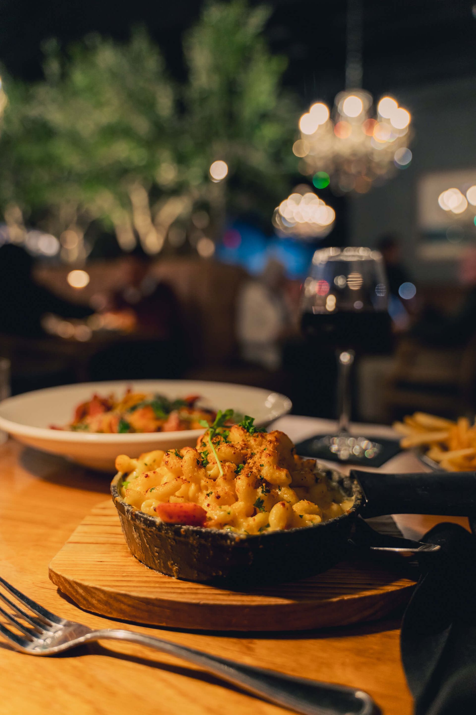 Rice dish in a black bowl on a wooden table, with a softly lit restaurant background