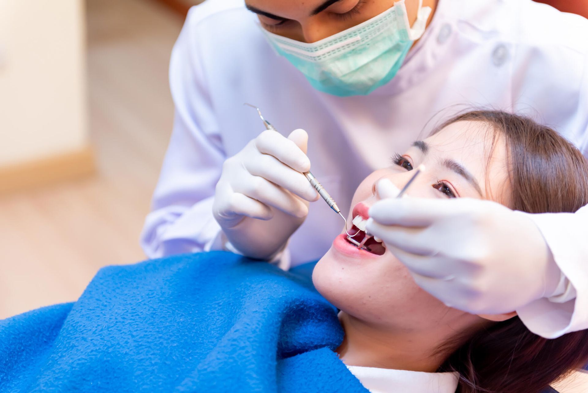 Dentist examining a patient's teeth in a dental office. The patient is in a chair.