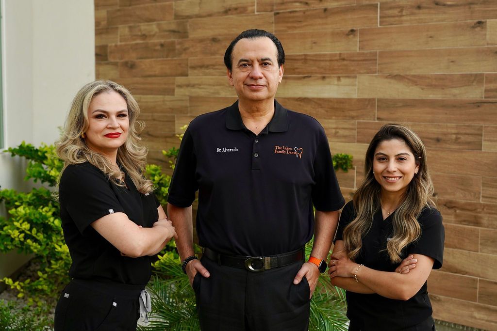 A man and two women are posing for a picture in front of a wooden wall.