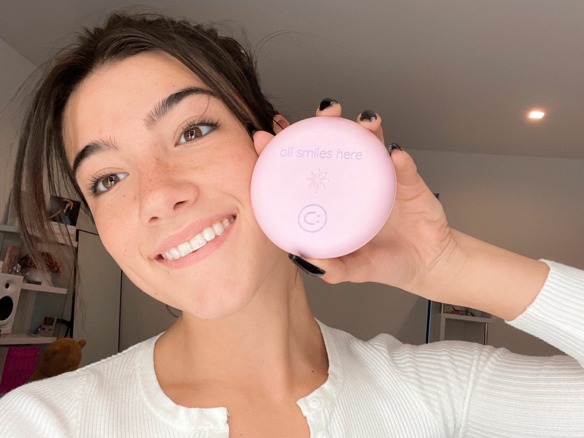 A woman is smiling while holding a pink object in her hand.