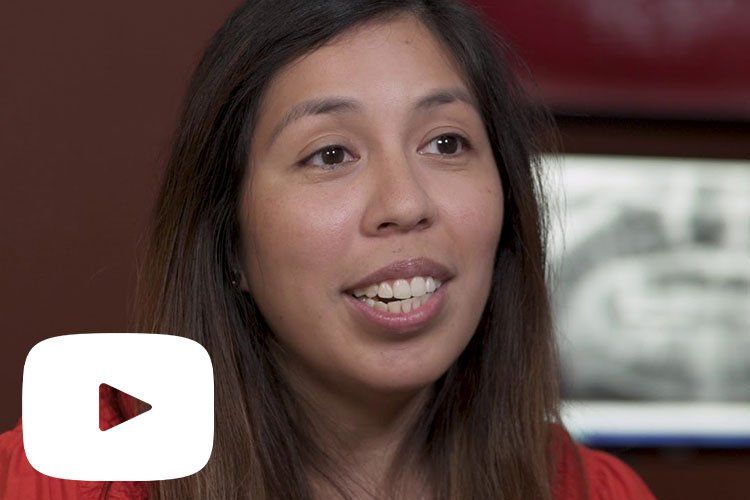 A woman is smiling in front of a youtube play button