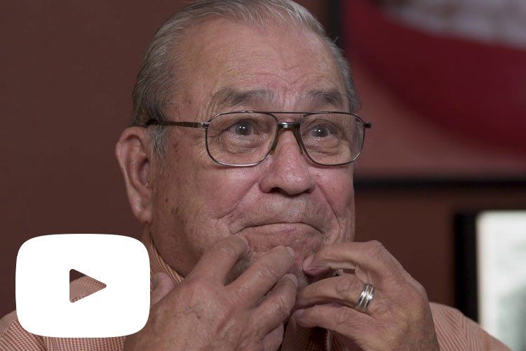 An elderly man wearing glasses and a ring on his finger.