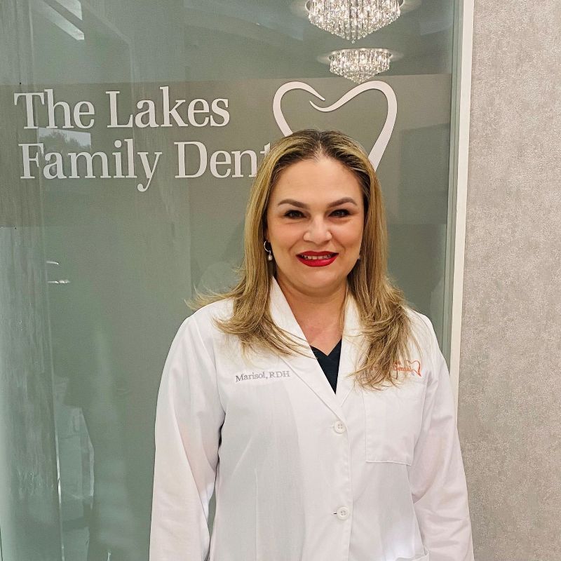 A woman in a white coat is standing in front of a glass door.