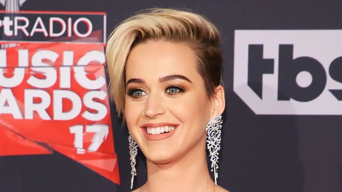 Katy perry is smiling on the red carpet at the radio music awards.