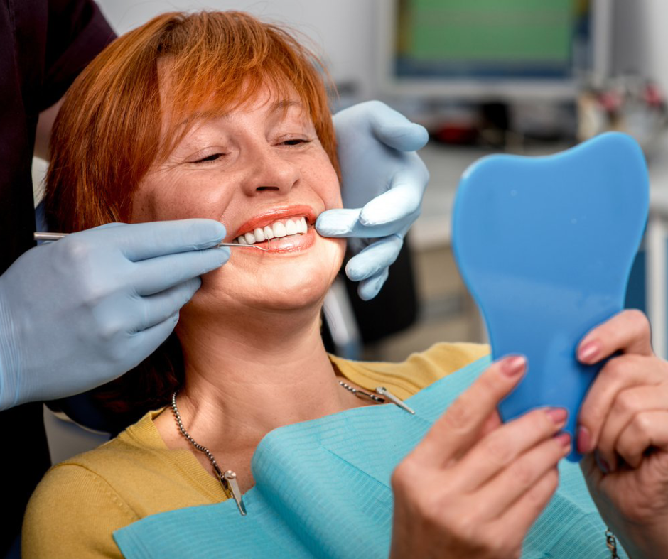 A woman is looking at her teeth in a mirror