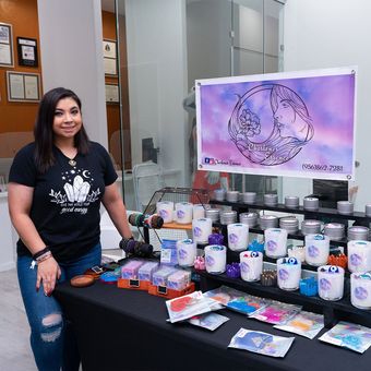 A woman in a black shirt is standing next to a table with candles on it.