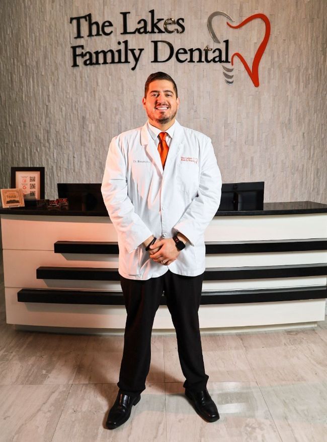A man in a lab coat is standing in front of a dental office.