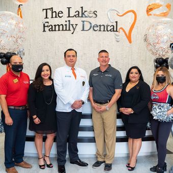 A group of people standing in front of a sign that says the lakes family dental