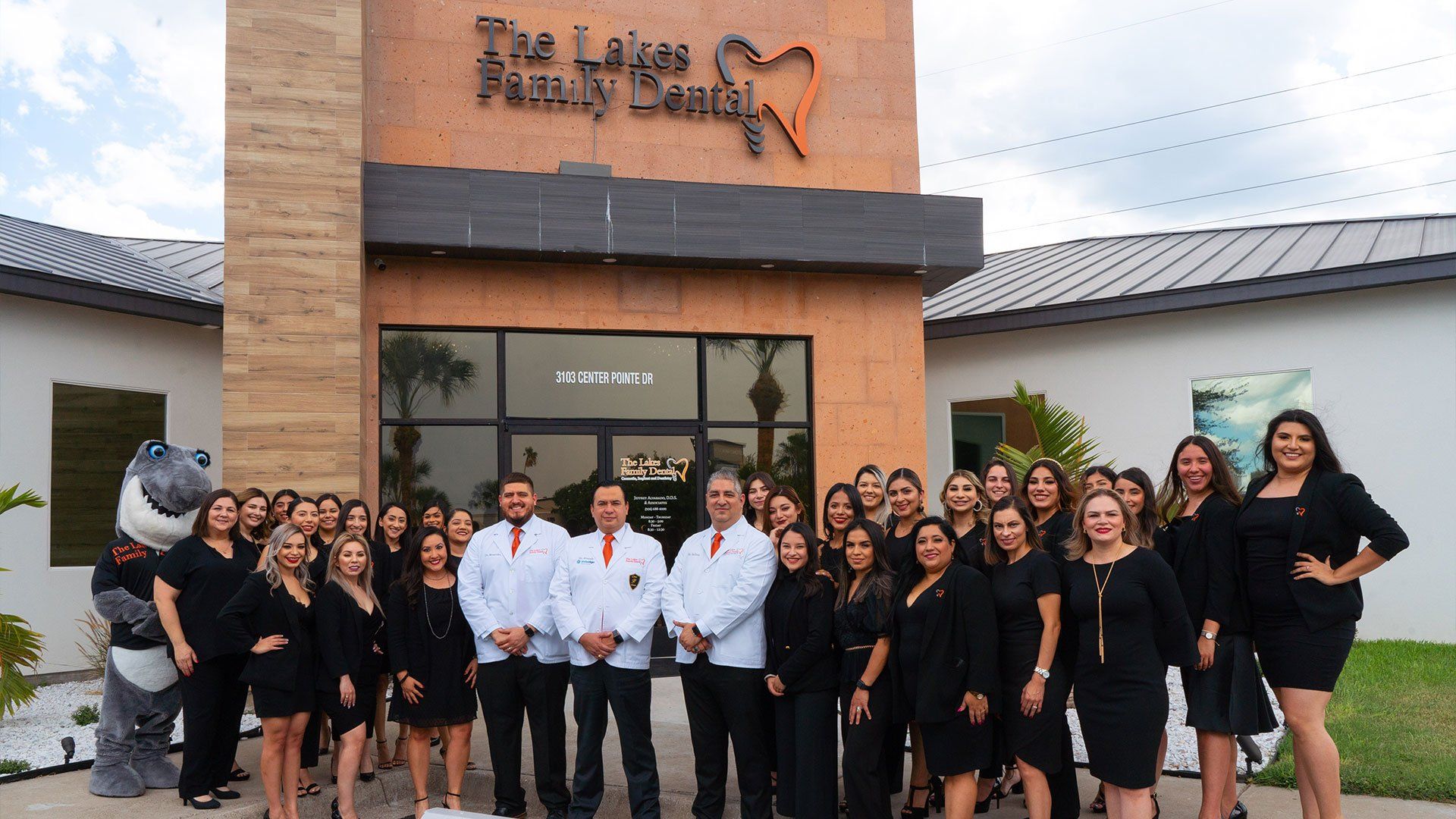 A group of people are posing for a picture in front of a dental office.
