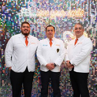 Three men in white coats and ties are posing for a picture.