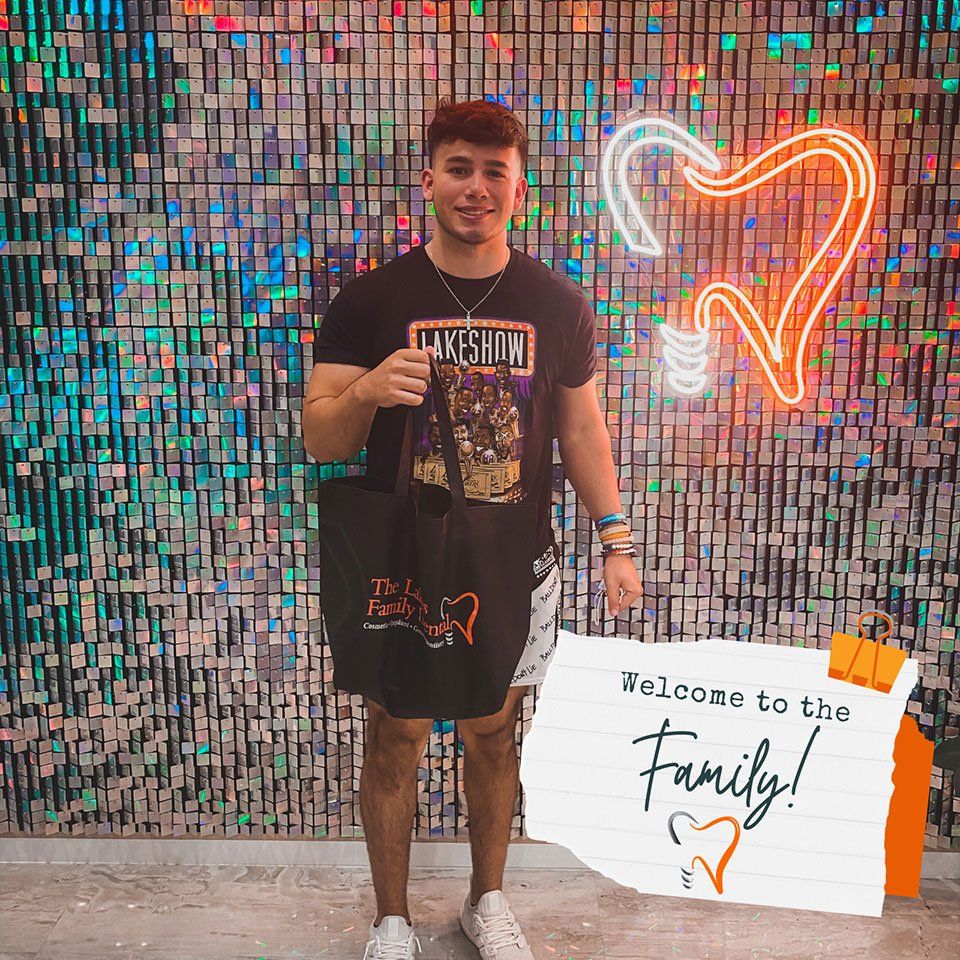 A man is standing in front of a wall holding a sign that says `` welcome to the family ''.