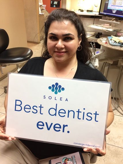 A woman is holding a sign that says best dentist ever