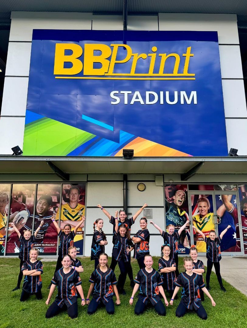 A Group Of People Are Posing In Front Of A Building That Says Bbprint Stadium — Dance Express Mackay In North Mackay, QLD