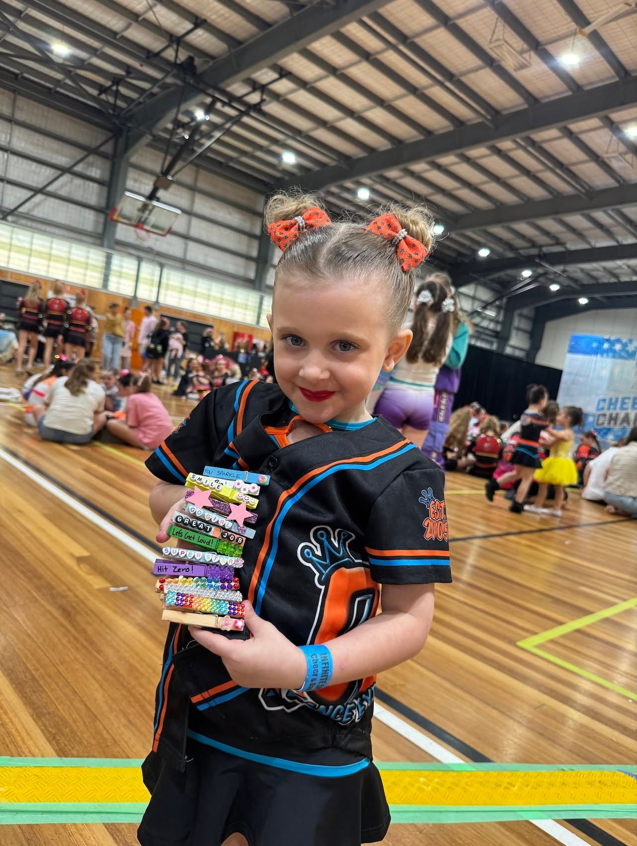 Smiling Child Holding a Colorful Bead Stack at a Lively Indoor Gym Event — Dance Express Mackay In North Mackay, QLD