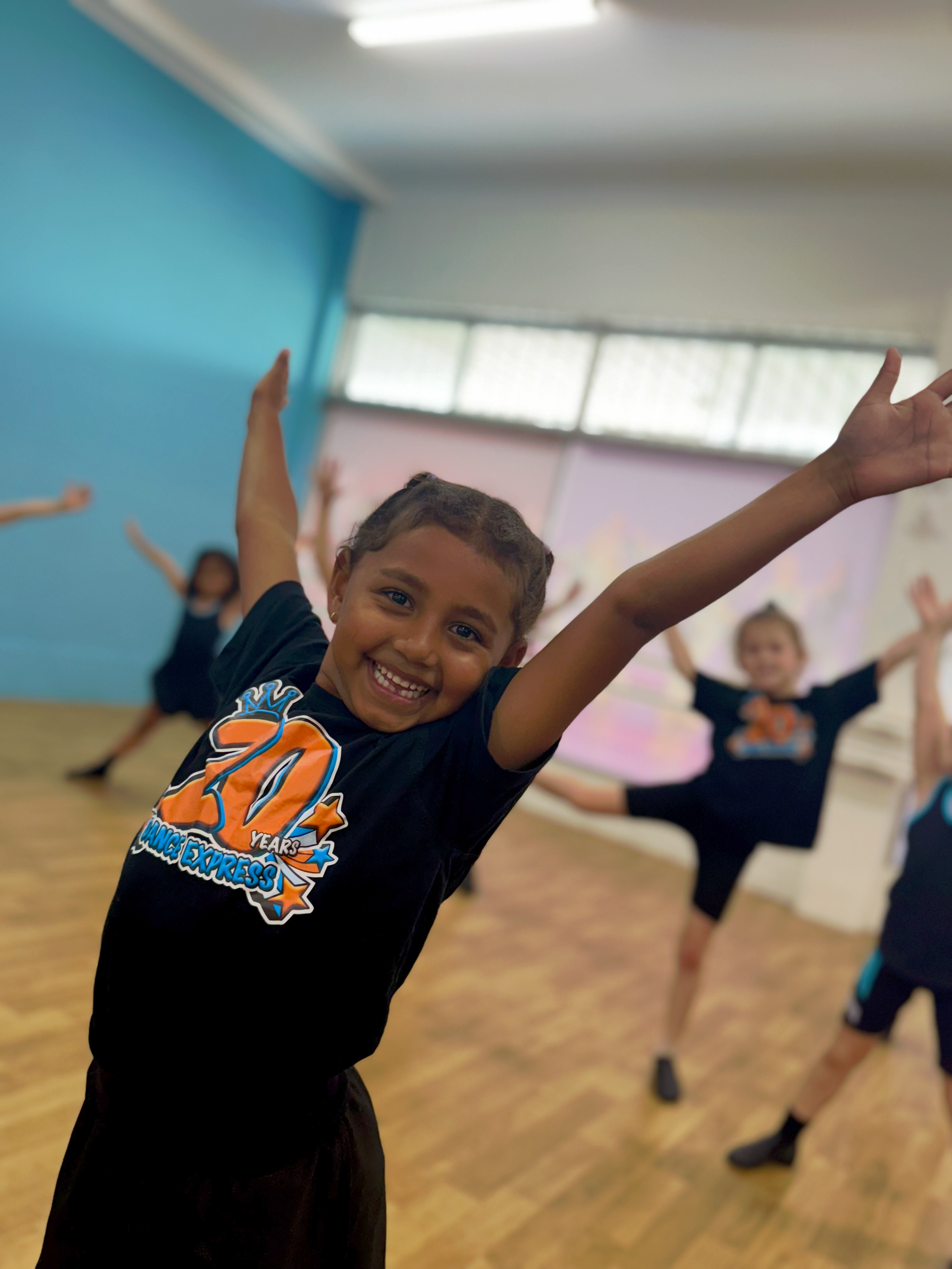 Smiling Girl In Black Shirt With Arms Outstretched, Dancing In A Studio — Dance Express Mackay In North Mackay, QLD