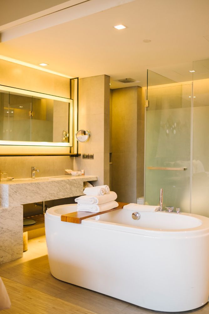 A bathroom with a bathtub, sink, mirror and shower.