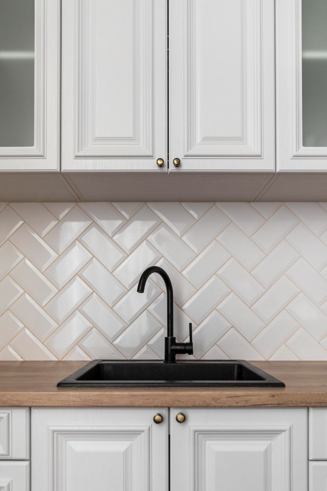 A kitchen with white cabinets and a black sink.