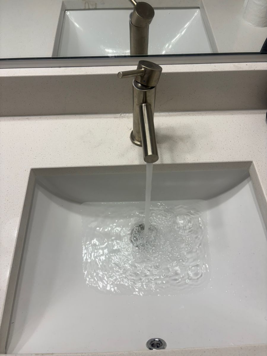 Chrome faucet running into a white bathroom sink
