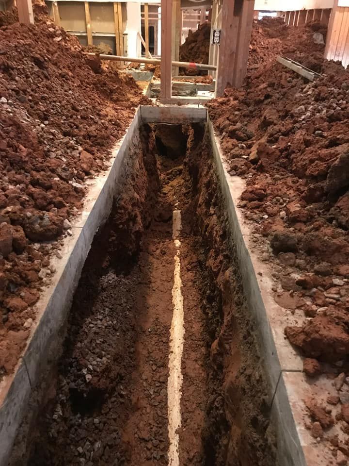 A drain pipe is being installed in a trench filled with dirt.