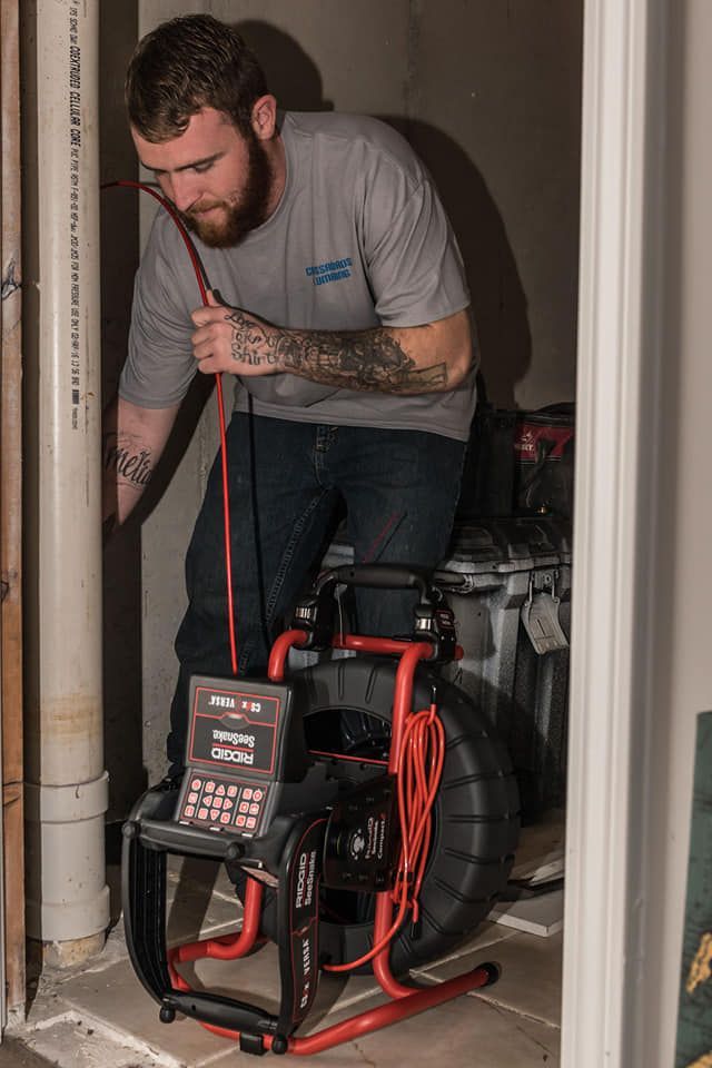 A man is using a camera to look at a pipe.