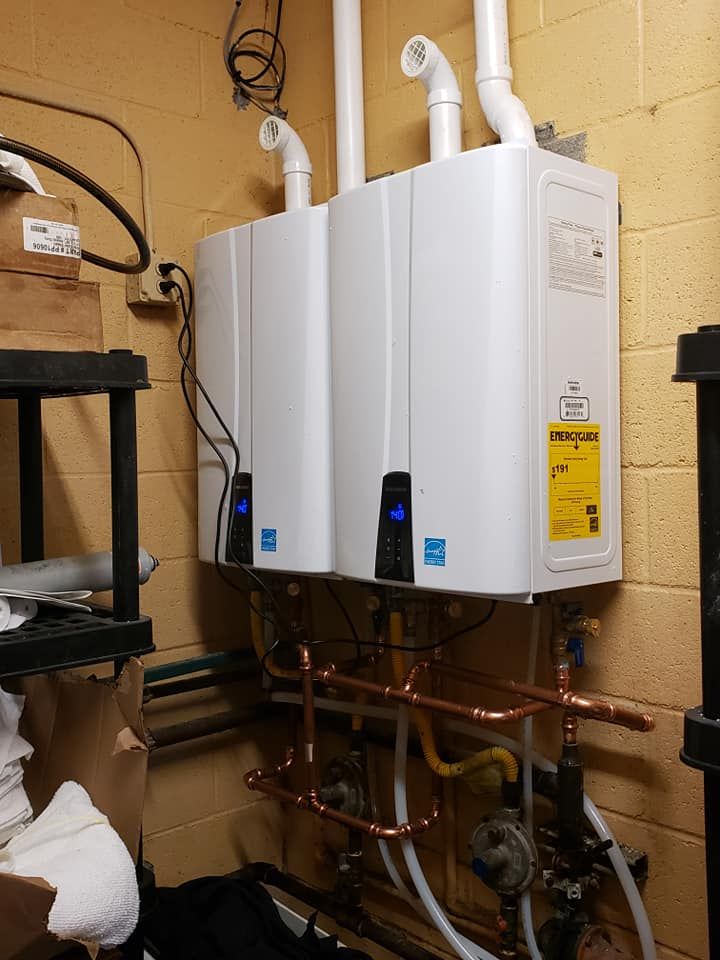 Two water heaters are hanging on a wall in a room.
