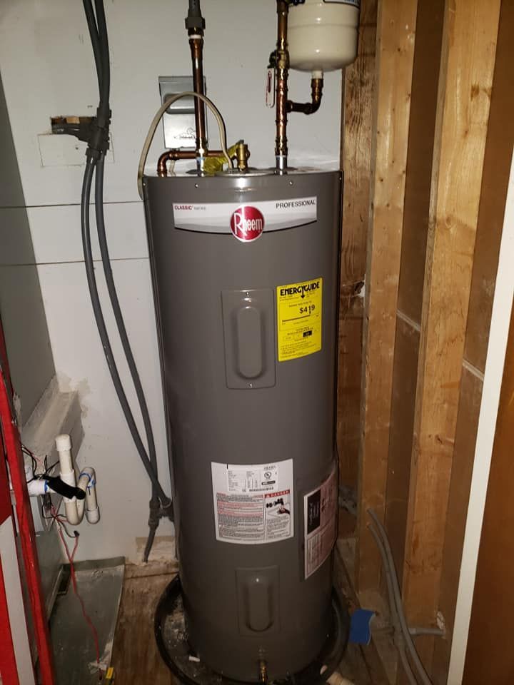 A gray water heater is sitting in a corner of a room.