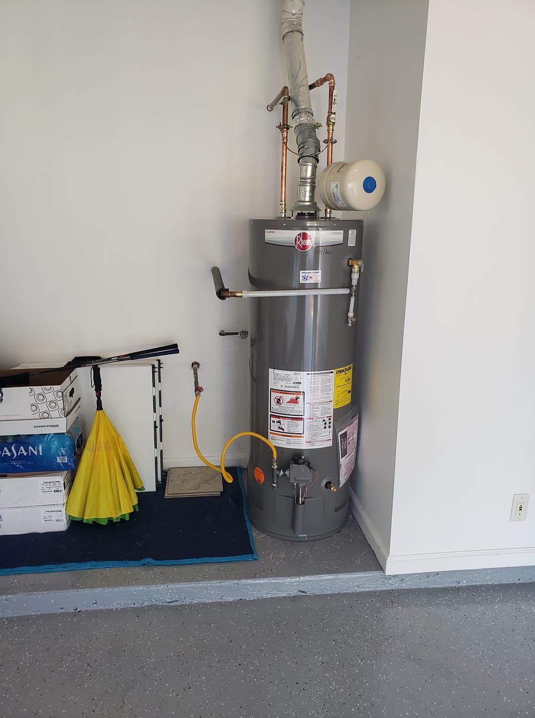 A water heater is sitting in a room next to a wall.