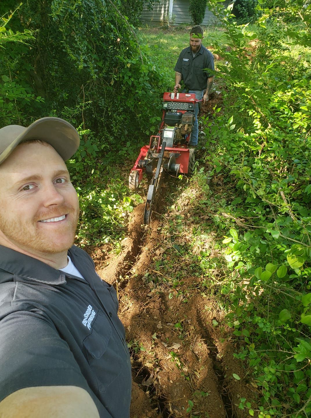A man is standing next to a machine in the woods.