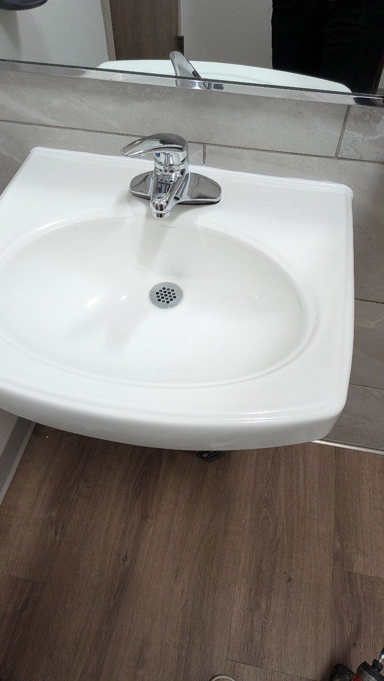 White bathroom sink with chrome faucet and a wooden floor below.