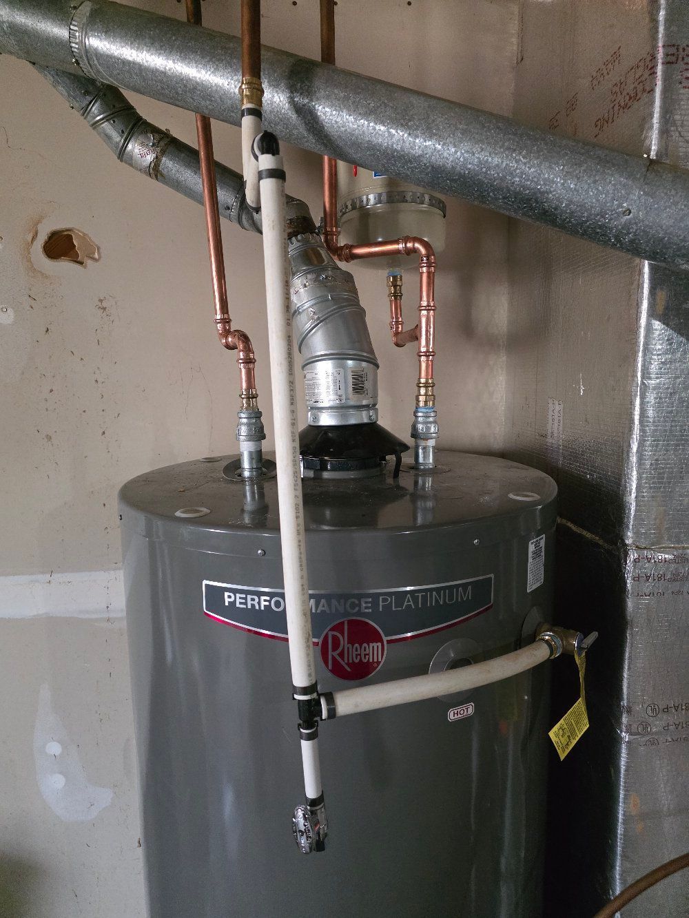 Gray water heater with copper pipes and venting in a basement utility room