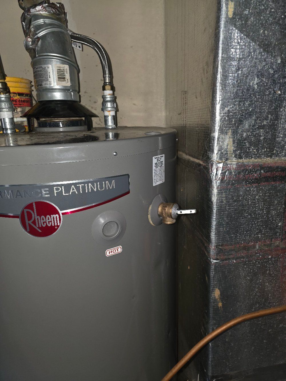Gray Rheem Platinum water heater in a utility room with attached pipes and venting.