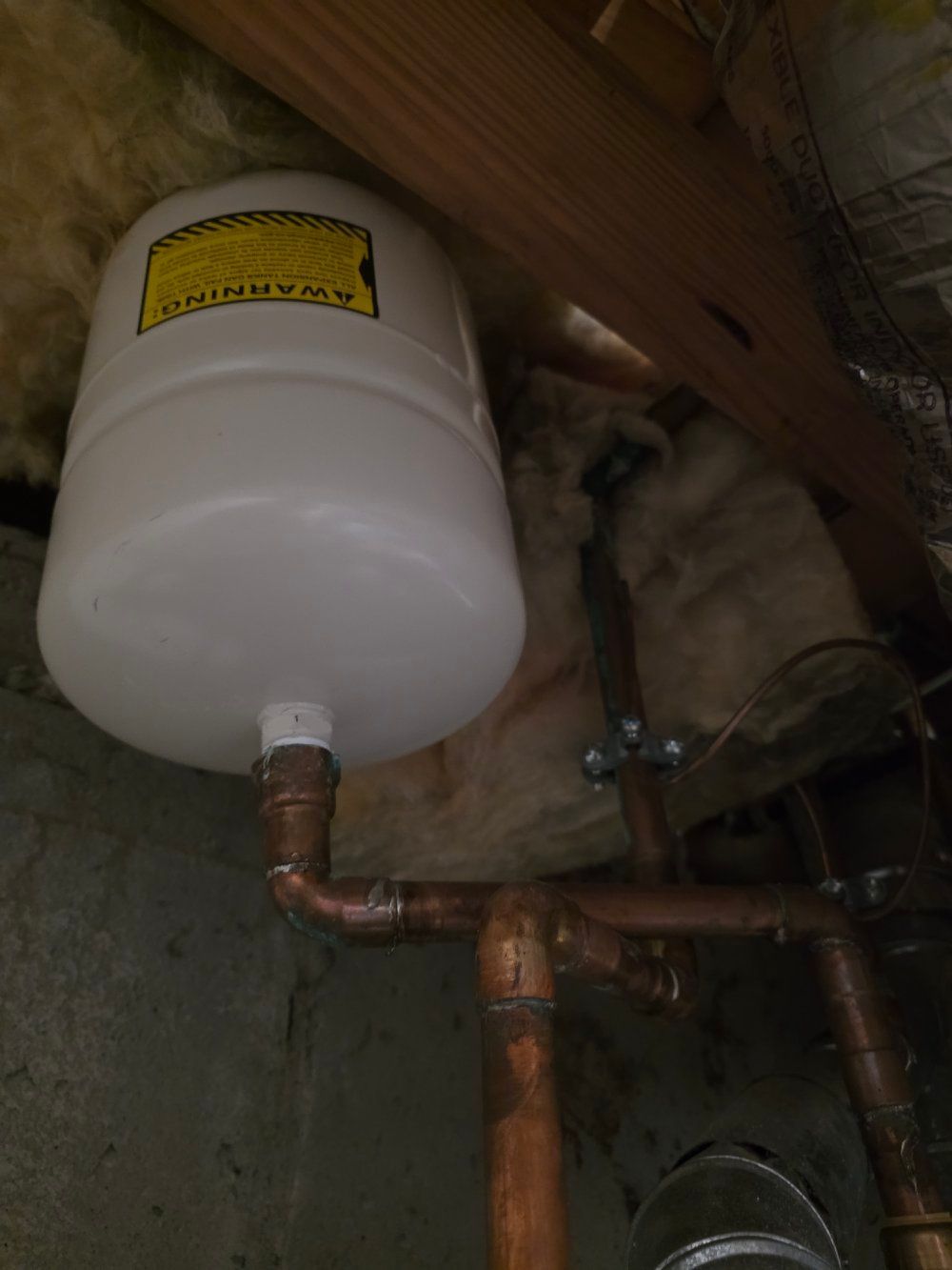White water heater tank with copper pipes in an attic or crawlspace
