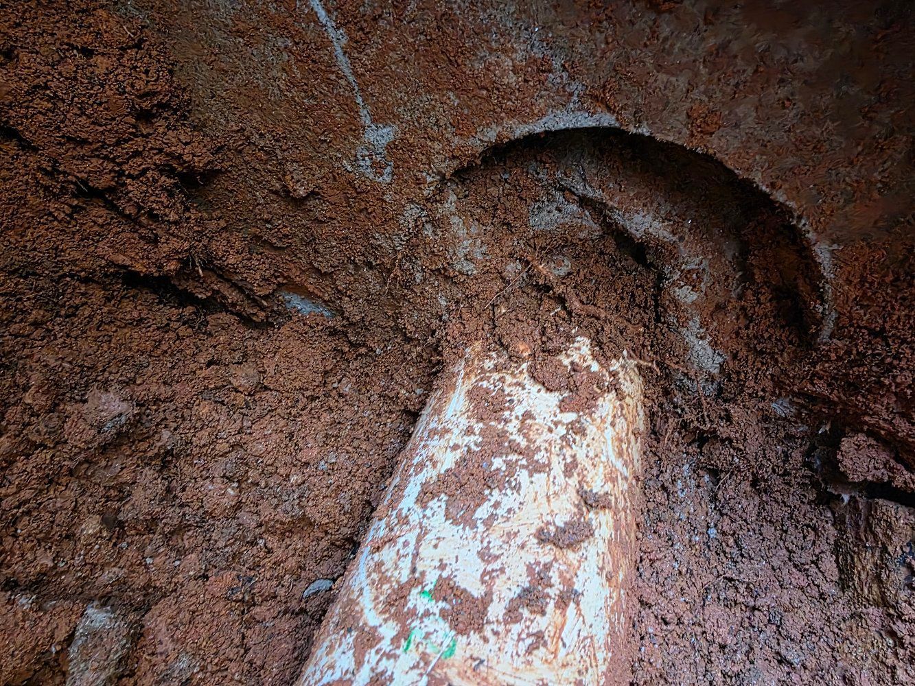 Close-up of a rusted metal surface with a curved, dark cutout and peeling white paint