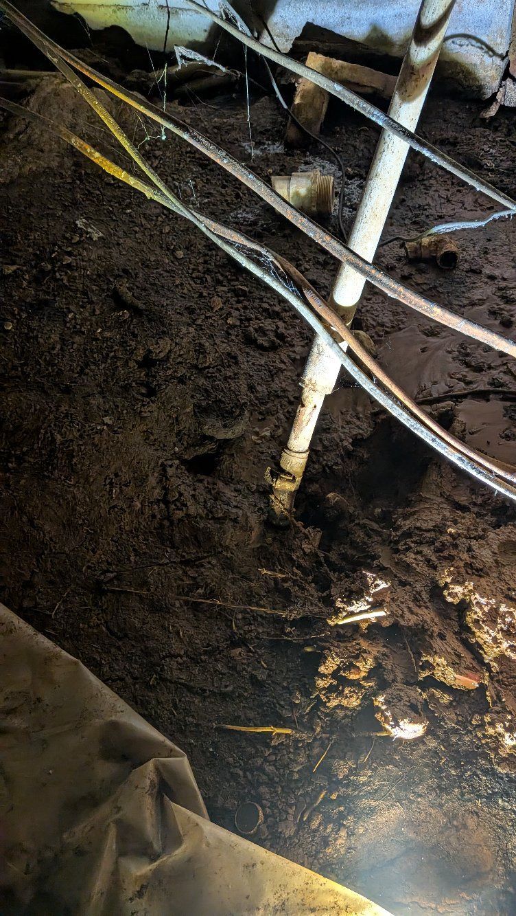 White support poles and cables in a muddy trench, with a bright light shining from the bottom.